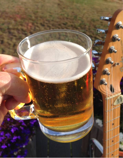 A glass of beer held up near a guitar