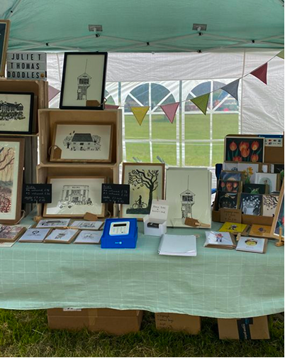 Arts and crafts booth display with framed pieces and handmade goods