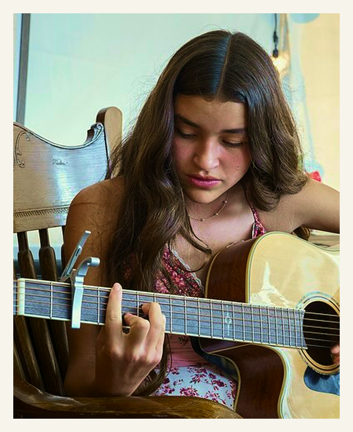 Student practicing guitar during a music lesson