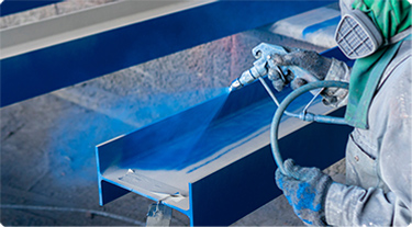 Person dressed in safety gear coating a surface blue