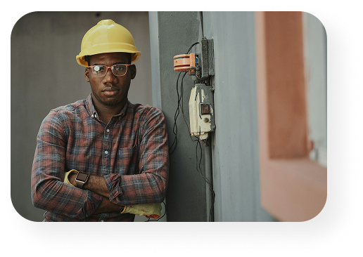 a man standing with his arms crossed wearing a hard hat