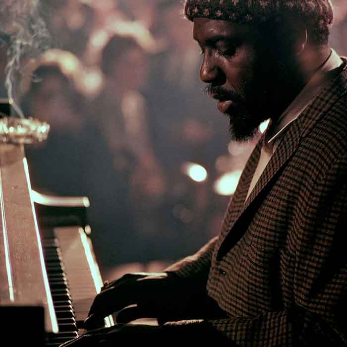 A side view of Theolonious Monk playing the piano.