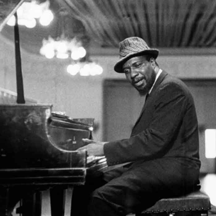 A side view of Theolonious Monk playing the piano.