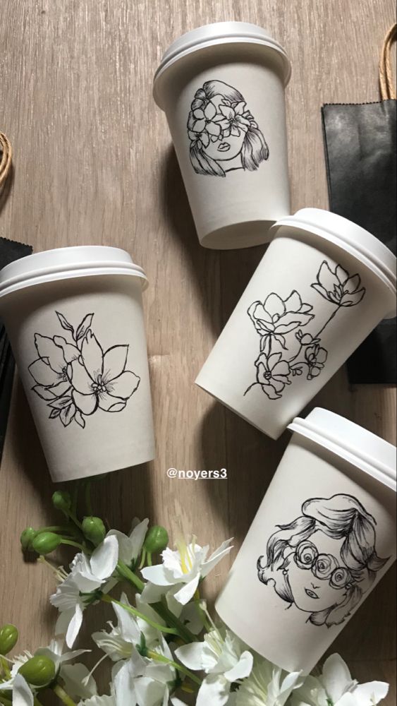 white paper coffee cups with flowers drawn on