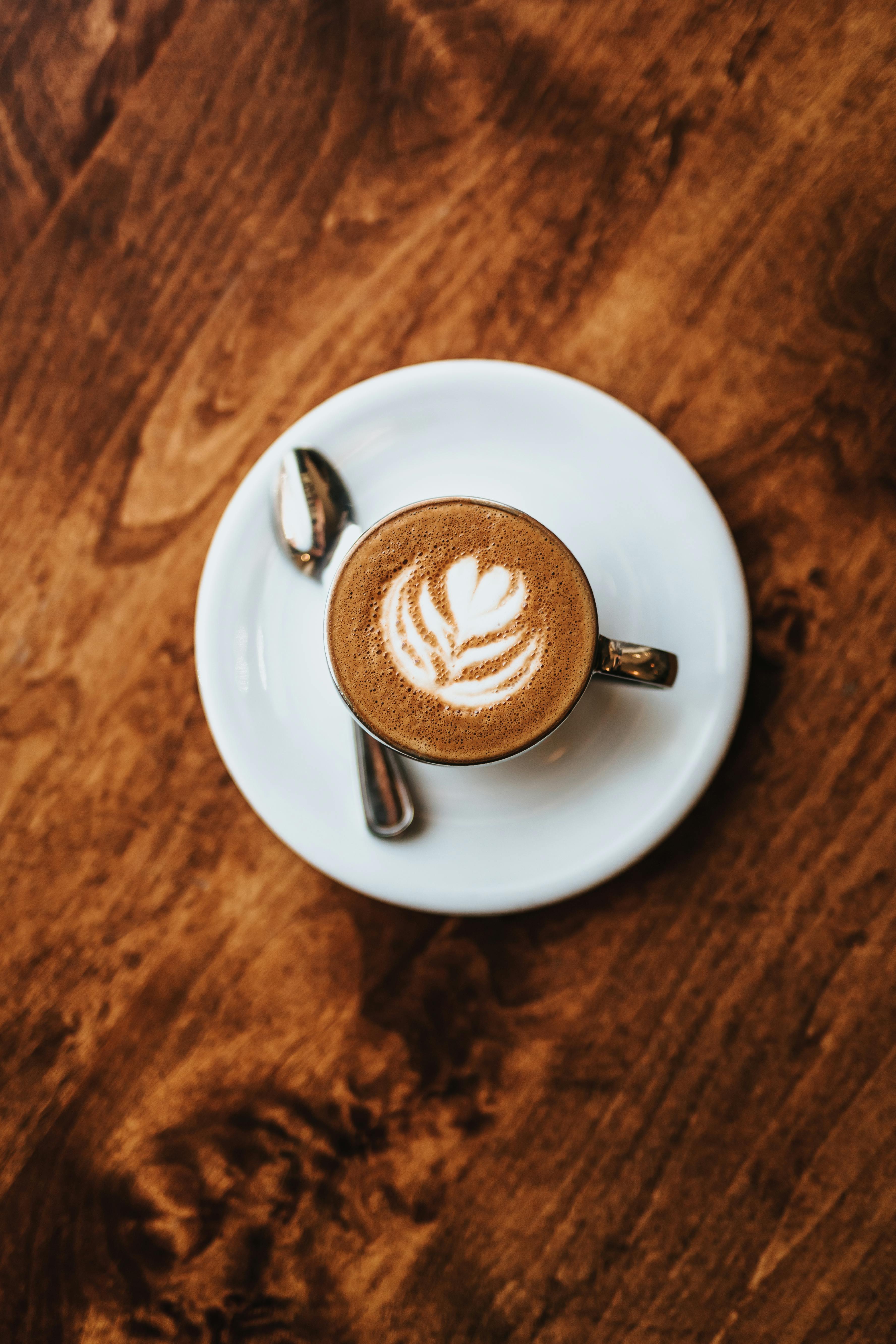 latte art in a white mug on a brown wooden table